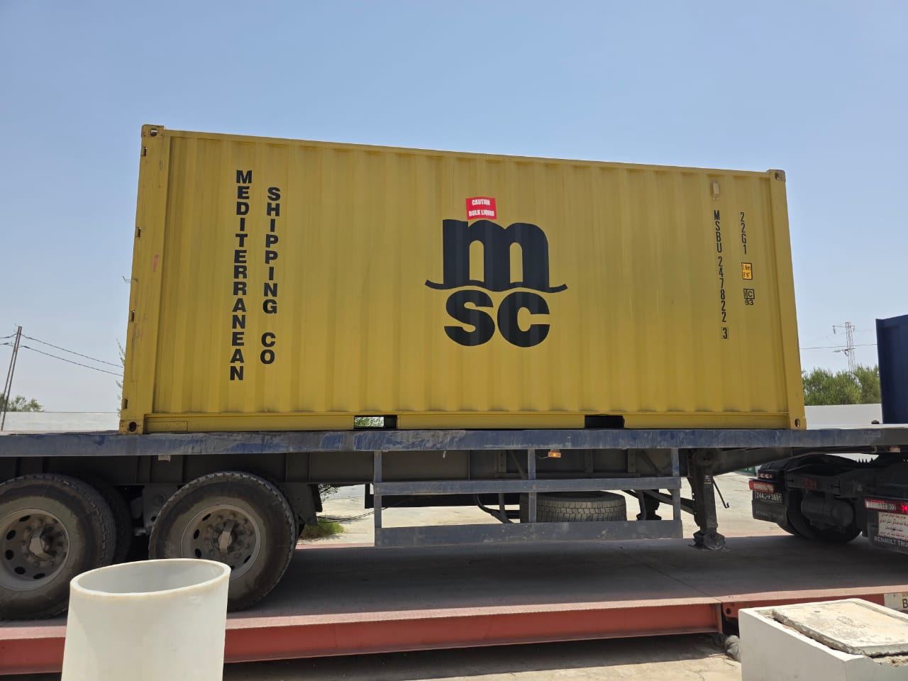Maritime shipping container positioned on a road-transport trailer