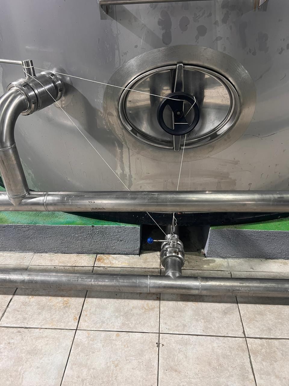 Close view of an AGRO OLEA metallic storage tank with fixed piping, valves and transfer connections